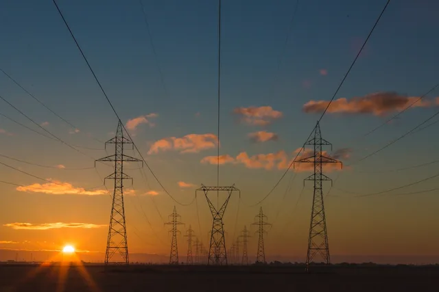Electricity transmission towers at dusk—illustrative context for UK retail energy market consolidation, not a specific E.ON or Ovo facility.
