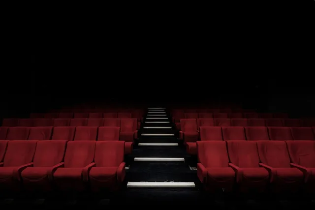 Darkened cinema auditorium rows—editorial metaphor for biopic release debates; not film stills or likeness from Michael