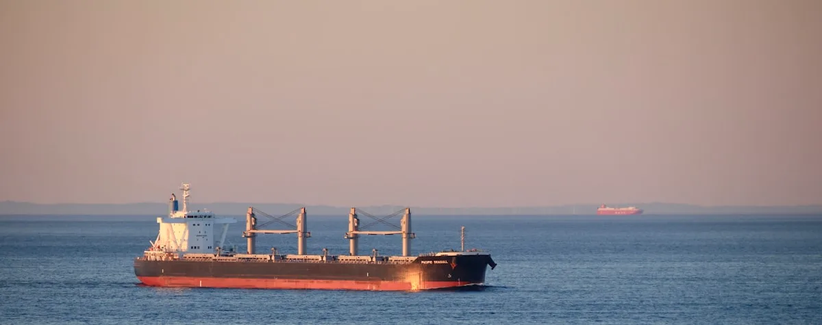 Red commercial vessel transiting open water under a gray sky — illustrative imagery for the contested Gulf shipping environment after Sunday's drone strikes and Trump's rejection of Iran's ceasefire reply